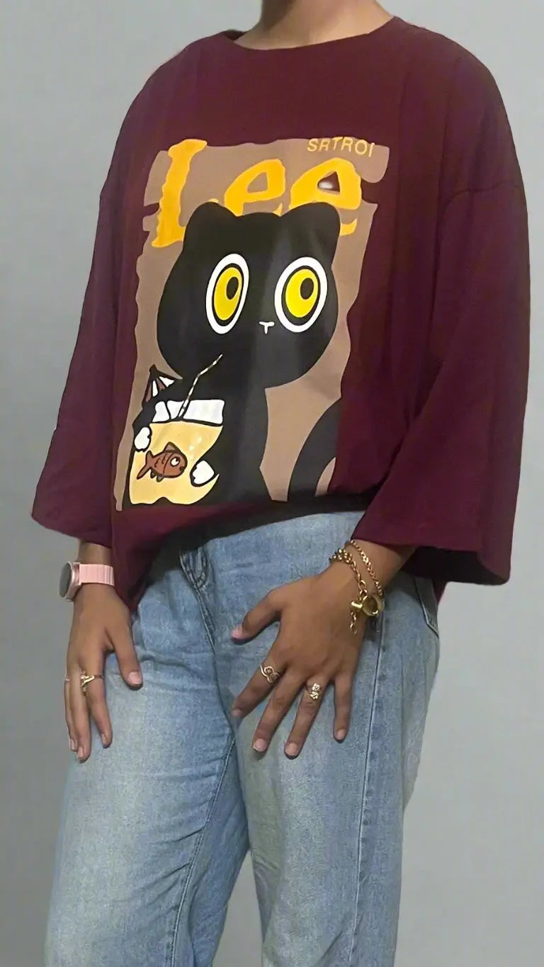 Person wearing a maroon sweatshirt with a cartoon design and light blue jeans against a white background