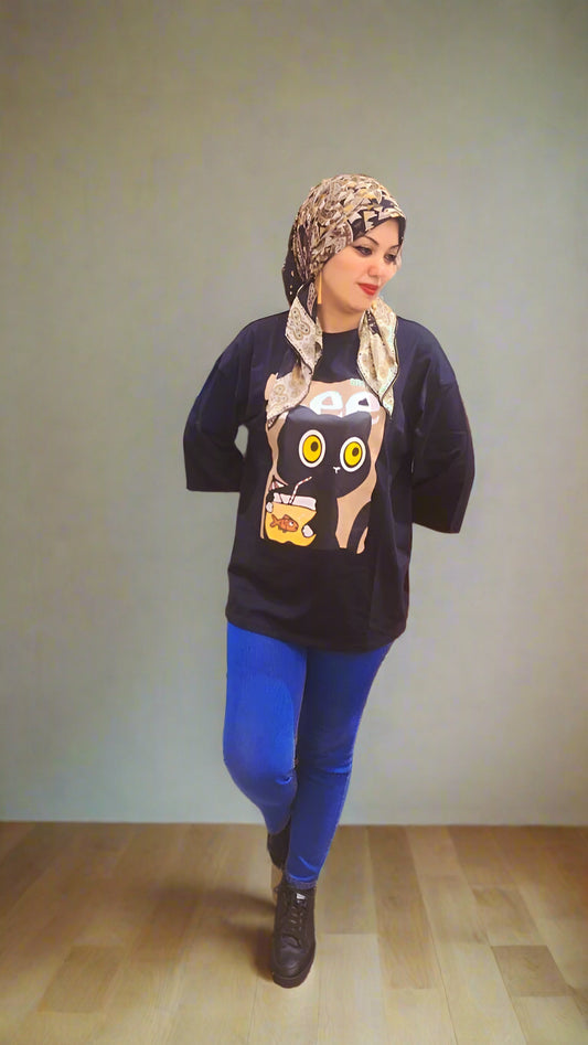 Woman wearing a dark sweater with a graphic design and blue pants in an indoor setting.
